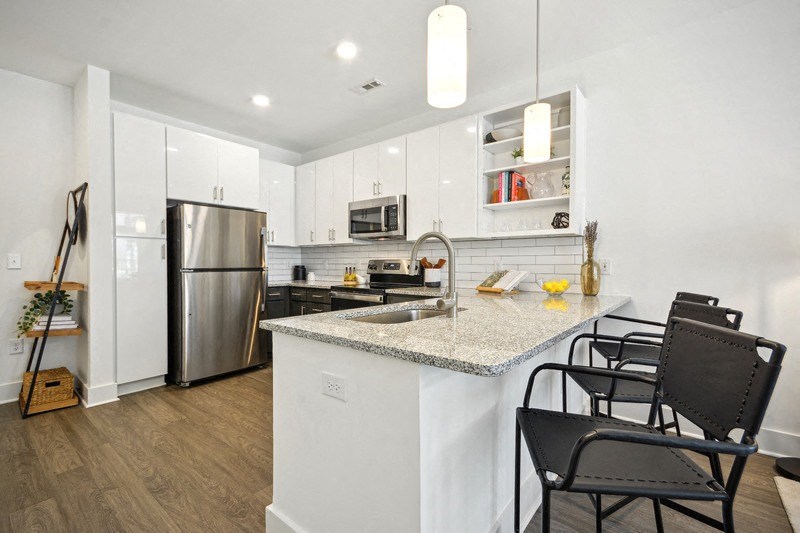 a kitchen with a granite counter top and a stainless steel refrigerator at Link Apartments® 4th Street, Winston-Salem, North Carolina