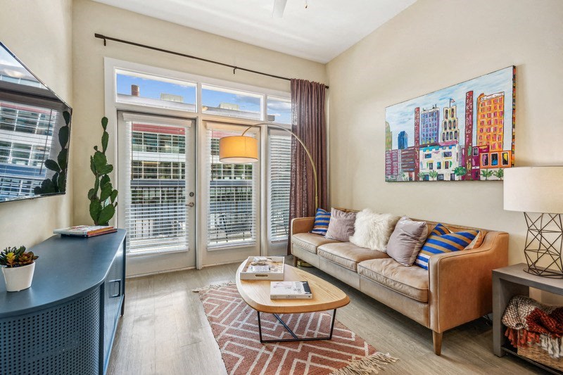 a living room with a couch and a tv and sliding glass doors at Link Apartments Innovation Quarter, North Carolina