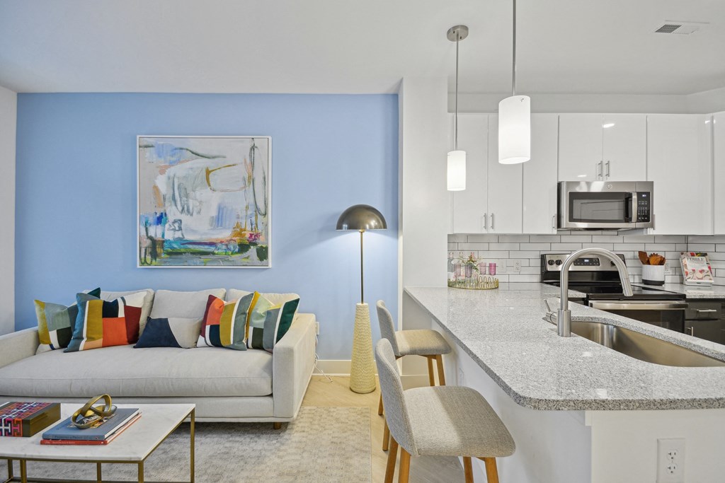 a living room with a couch and a kitchen at Link Apartments® Calyx, Chapel Hill, NC