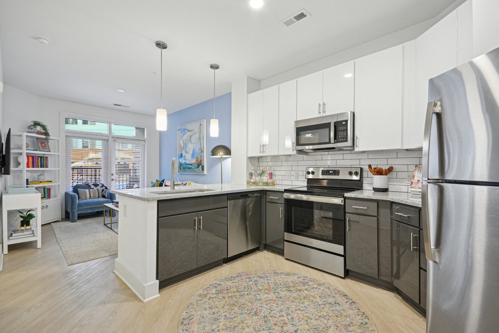a kitchen with stainless steel appliances and white cabinets at Link Apartments® Calyx, Chapel Hill