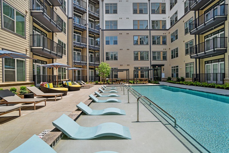 an outdoor pool with lounge chairs in front of an apartment building at Link Apartments® NoDa 36th, North Carolina
