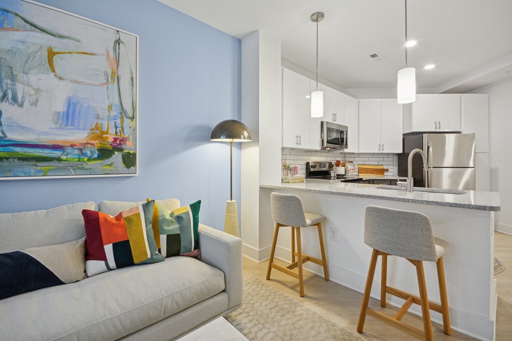a living room with a couch and a kitchen with a bar at Link Apartments® Calyx, North Carolina