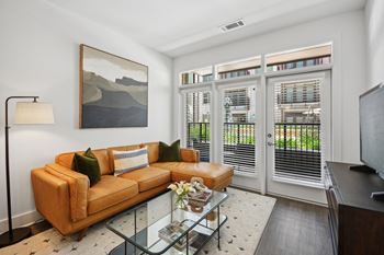 A living room with a tan couch and a painting on the wall. at Link Apartments® 4th Street, Winston-Salem, North Carolina