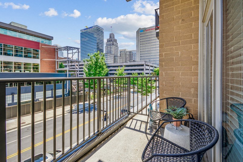 the view of the city from the balcony of a condo with a chair and table at Link Apartments Innovation Quarter, Winston Salem, NC, 27101