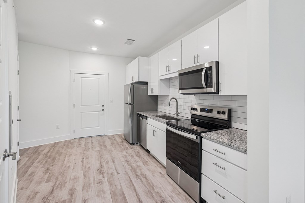 A kitchen with white cabinets and a black stove top oven at Link Apartments® CYKEL Apartments, Charlotte, NC