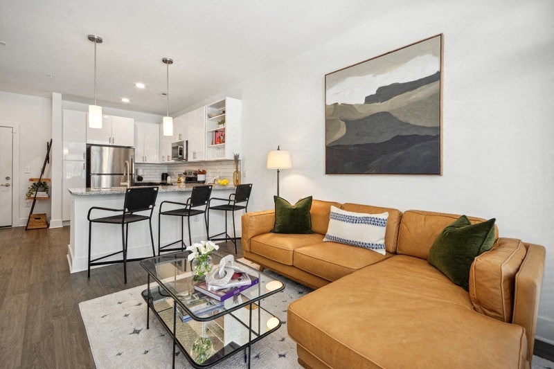 a living room and kitchen with a couch and a glass table at Link Apartments® 4th Street, North Carolina