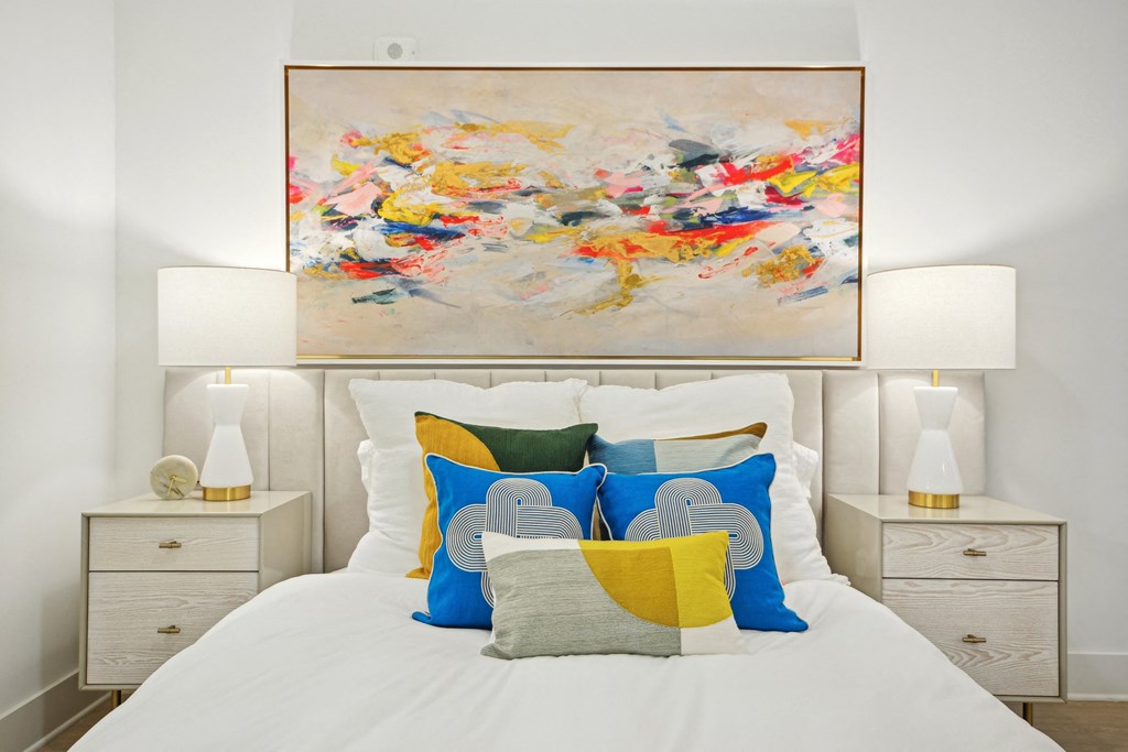 a bedroom with a bed with colorful pillows and a painting above it at Link Apartments® Calyx, Chapel Hill, NC
