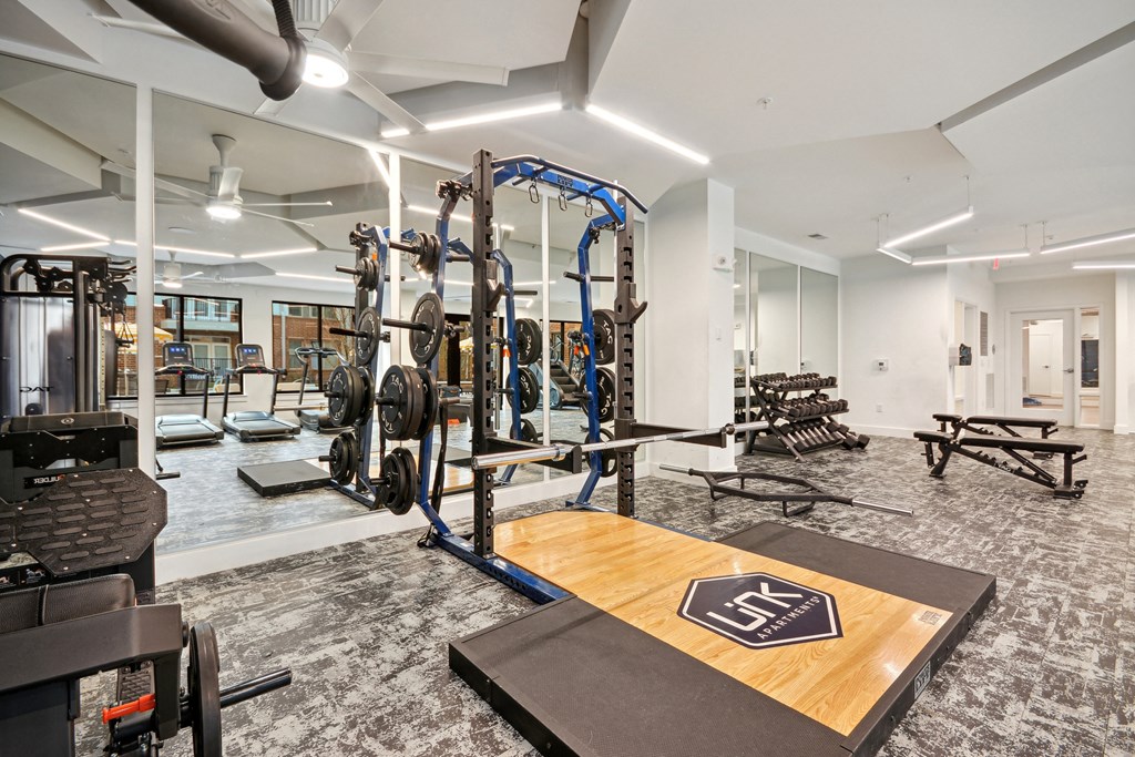 a gym with weights and cardio equipment in a building with white walls at Link Apartments® Calyx, Chapel Hill, 27517