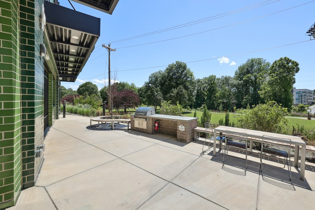 A sunny day at the park with a bench and a picnic table at Link Apartments® CYKEL Apartments, Charlotte