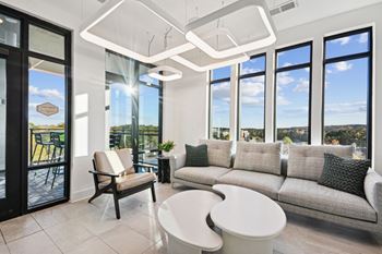 a living room with a couch and a table and windows at Link Apartments® Calyx, Chapel Hill North Carolina