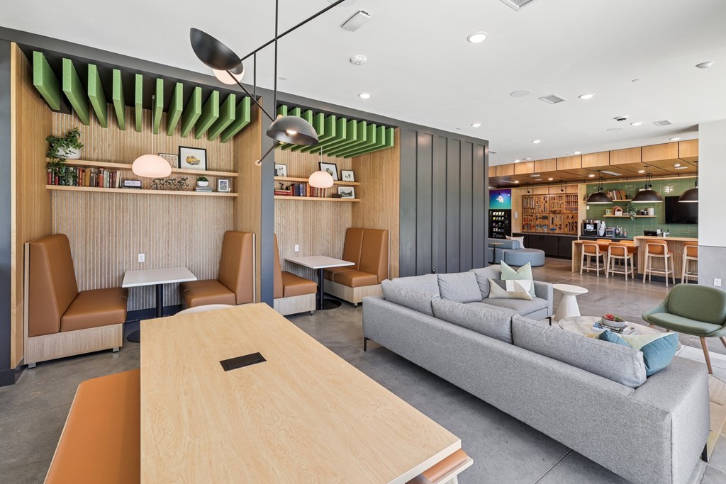 A modern living room with a grey sofa, wooden table and a green chair at Link Apartments® CYKEL Apartments, North Carolina