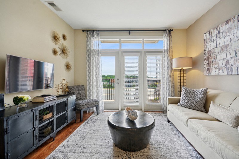a living room with a couch and a tv and a balcony at Link Apartments® Brookstown, Winston Salem