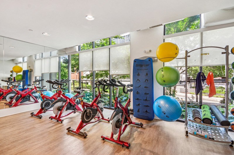 the gym has plenty of exercise equipment and floor to ceiling windows at Link Apartments Innovation Quarter, North Carolina