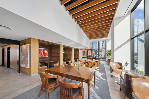 A modern dining area with wooden chairs and tables at Link Apartments® QPN, Long Island City, New York