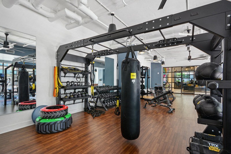 a gym with weights and cardio equipment on the walls and a wood floor at Link Apartments® 4th Street, Winston-Salem, 27101