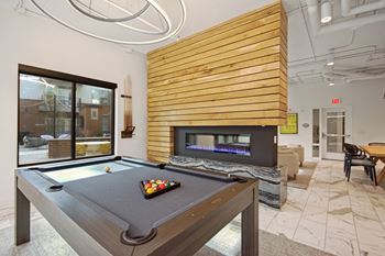 clubhouse with pool table and fireplace at the district at highland village apartments at Link Apartments® Calyx, North Carolina, 27517