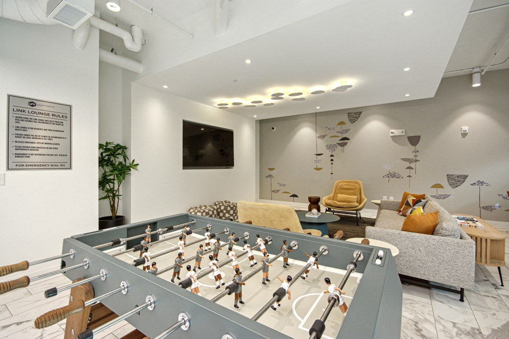 a game room with a foosball table and a couch at Link Apartments® Calyx, Chapel Hill, NC