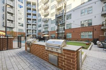 a barbecue grill on a brick wall in front of an apartment building at Link Apartments® Calyx, Chapel Hill North Carolina