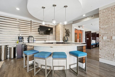 A kitchen with a bar stool and a brick wall.