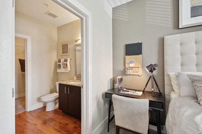 a bedroom with a desk and a bathroom with a toilet at Link Apartments® Brookstown, Winston Salem, NC, 27101