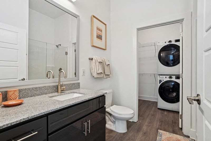 a bathroom with a sink and a toilet and a washing machine at Link Apartments® NoDa 36th, Charlotte, 28206