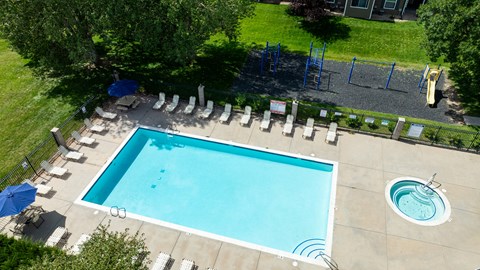 An aerial view of a swimming pool surrounded by lounge chairs and trees.