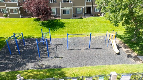 A playground with a slide, swings, and monkey bars.