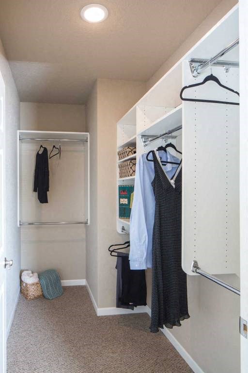a walk in closet with clothes hanging on the wall