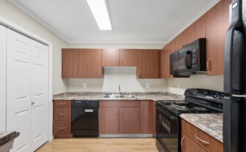 A kitchen with brown cabinets and black appliances.