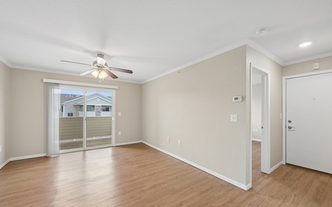 A room with a ceiling fan and sliding glass doors.