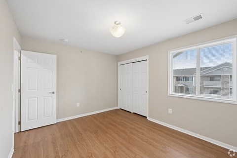 A room with a white door, a window with blinds, and a light on the ceiling.