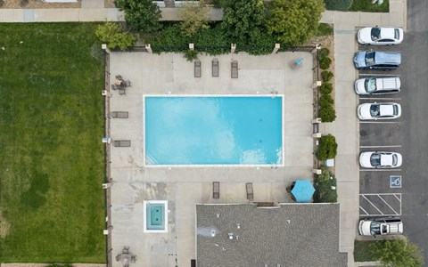An aerial view of a swimming pool surrounded by a parking lot.