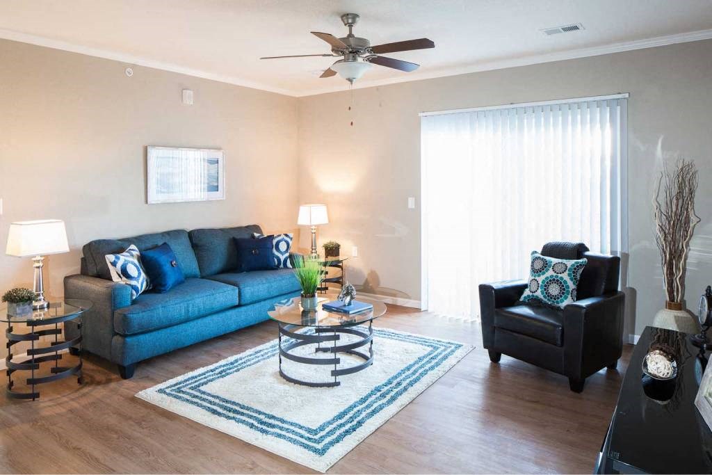 a living room with a couch and a chair and a ceiling fan