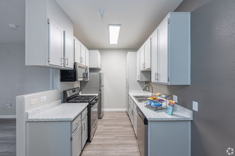 A kitchen with white cabinets and a grey countertop.