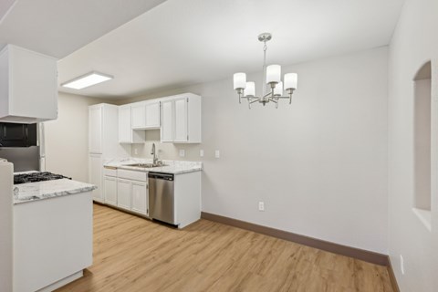 A kitchen with white cabinets and a wooden floor.