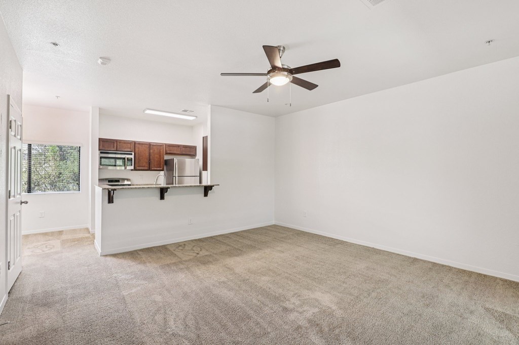A room with a ceiling fan and carpeted floor.