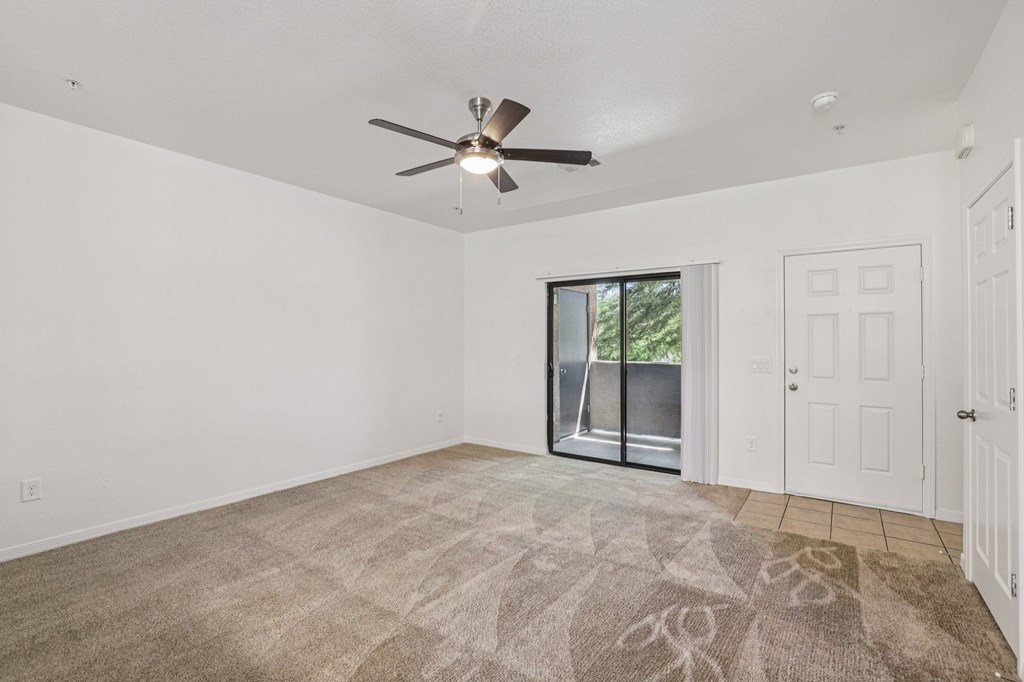 A room with a ceiling fan and a rug on the floor.