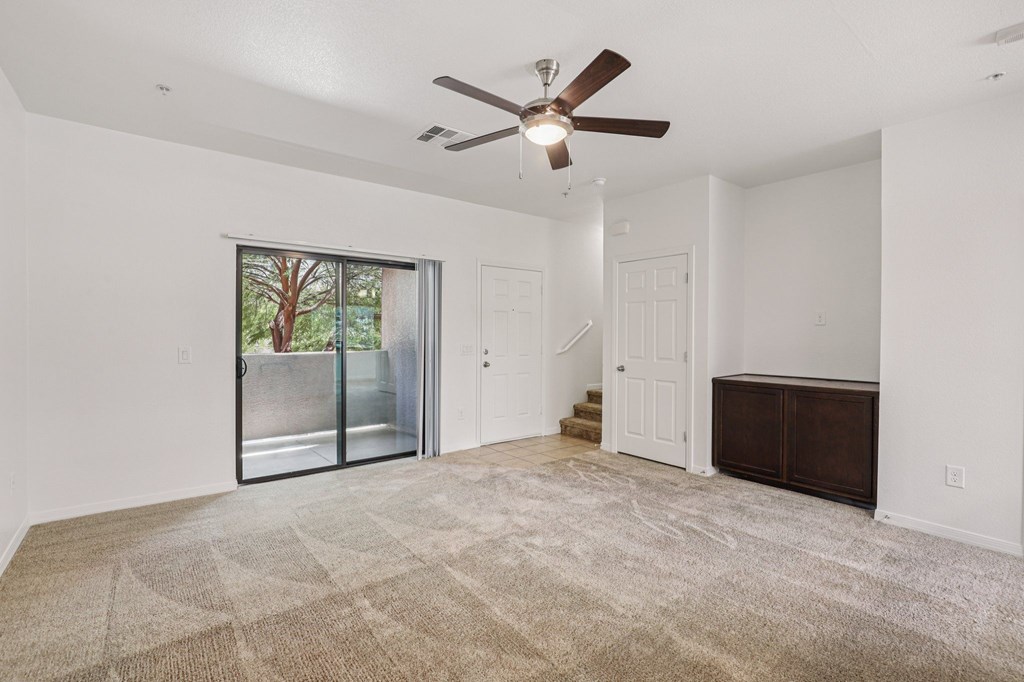A room with a fan and a carpet on the floor.