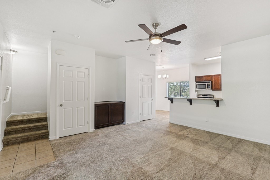 A living room with a ceiling fan and a brown rug.