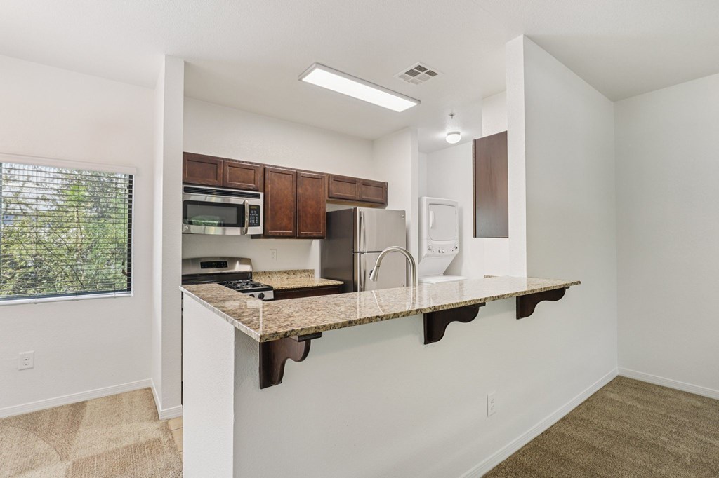 A kitchen with white walls and brown cabinets.