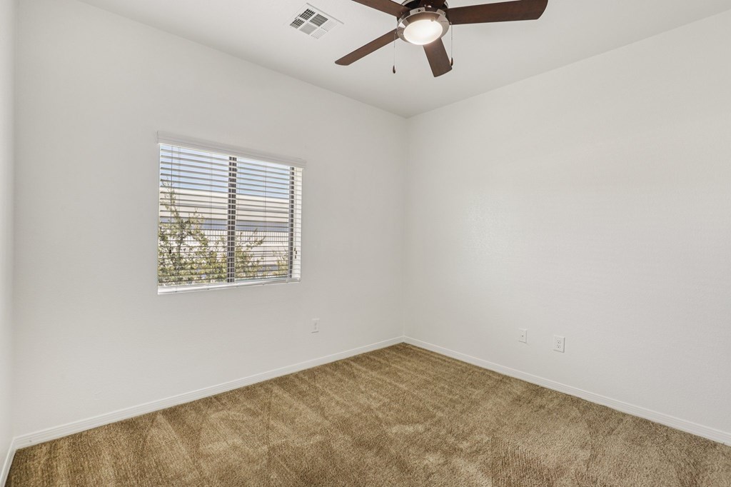 A room with a ceiling fan and carpeted floor.