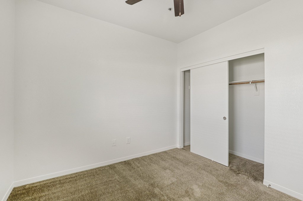 A room with a carpeted floor and a ceiling fan.