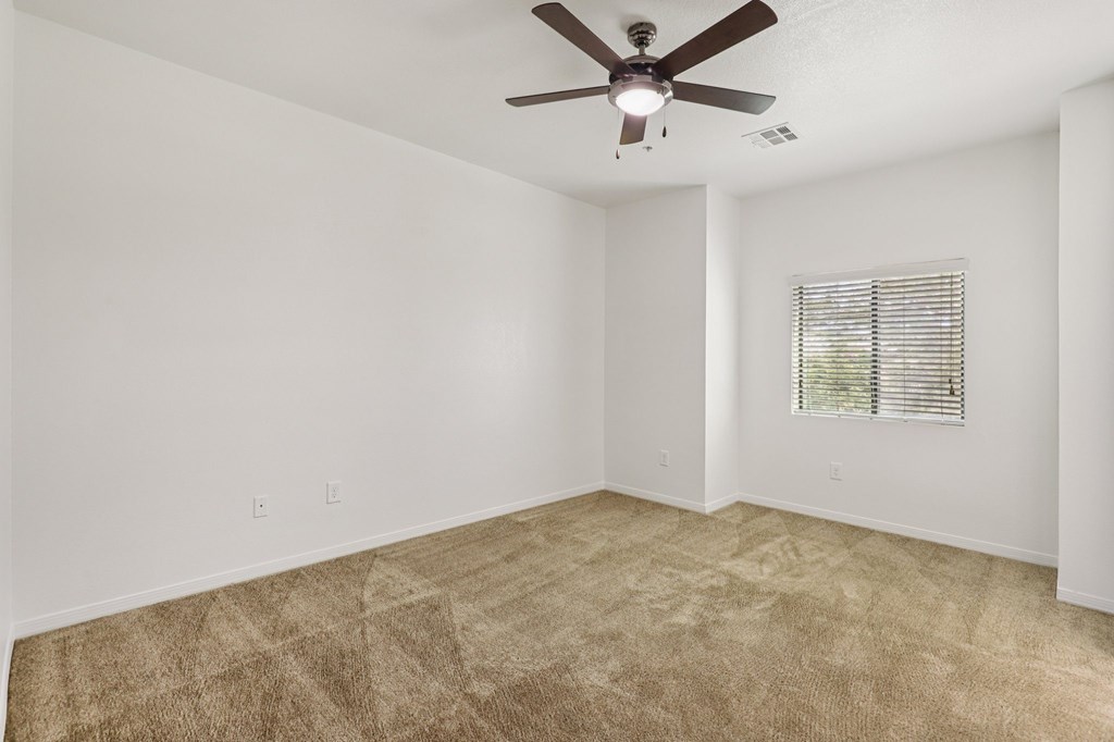 A room with a ceiling fan and carpeted floor.