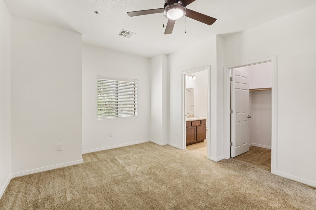 A room with a ceiling fan and carpeted floor.