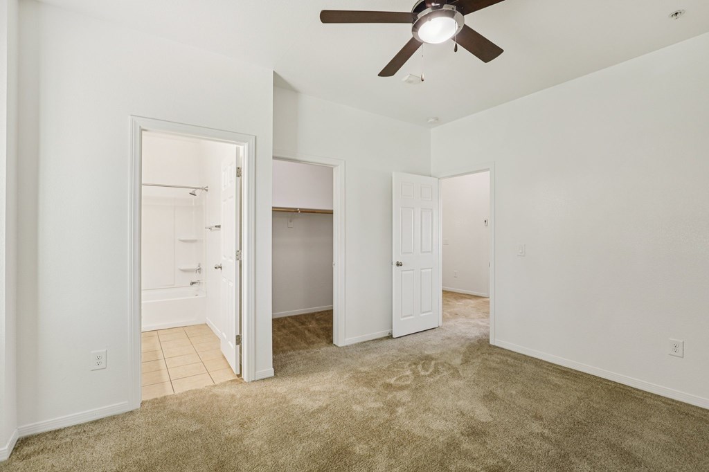 A room with a ceiling fan and carpeted floor.