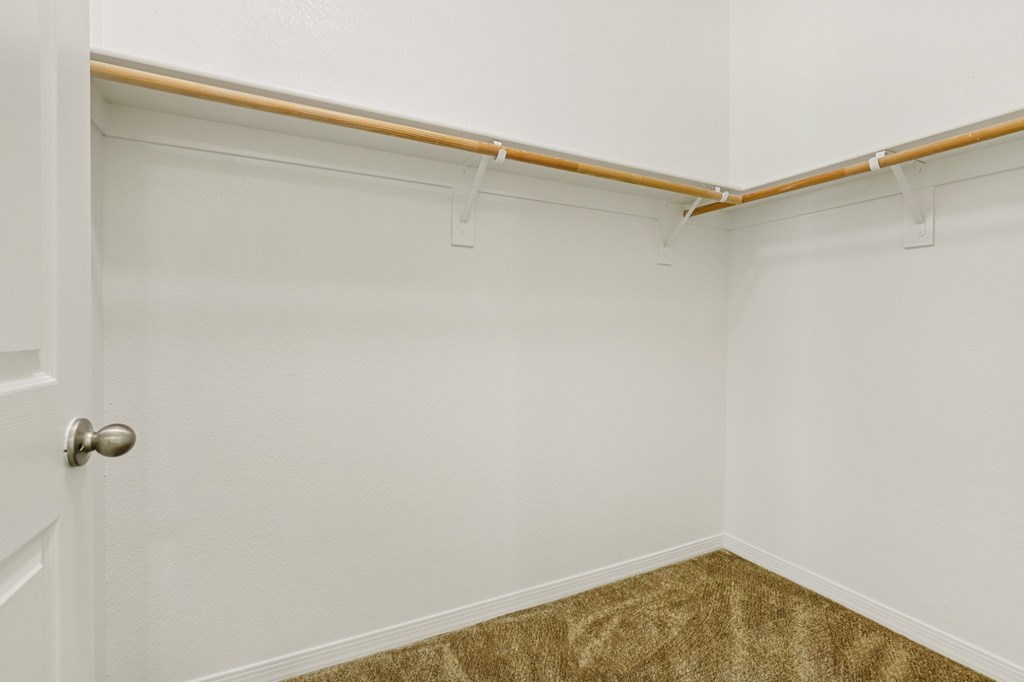 A white door is on the left of a room with a brown carpet.