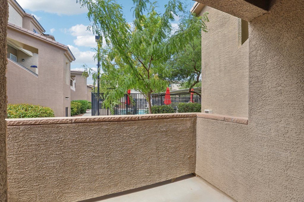 A wall with a window and a tree in the background.