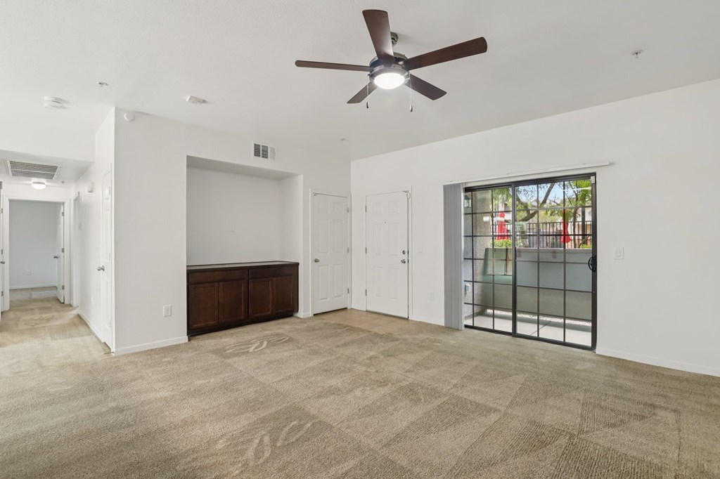 A room with a ceiling fan and carpeted floor.
