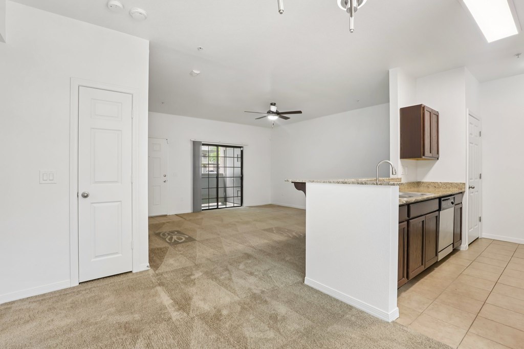 A spacious living room with a kitchen area in the background.