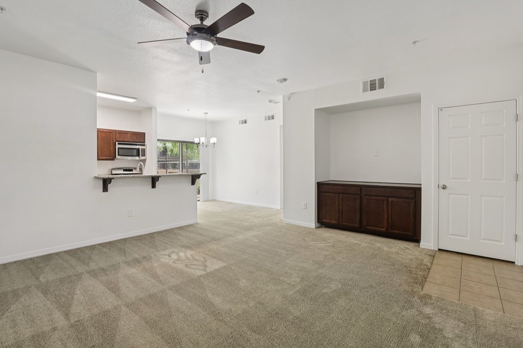 A room with a ceiling fan and carpeted floor.